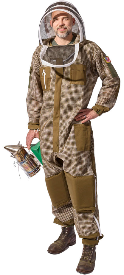 A man wearing a full beekeeping suit with a mesh face veil, holding a metal bee smoker against a plain white background.